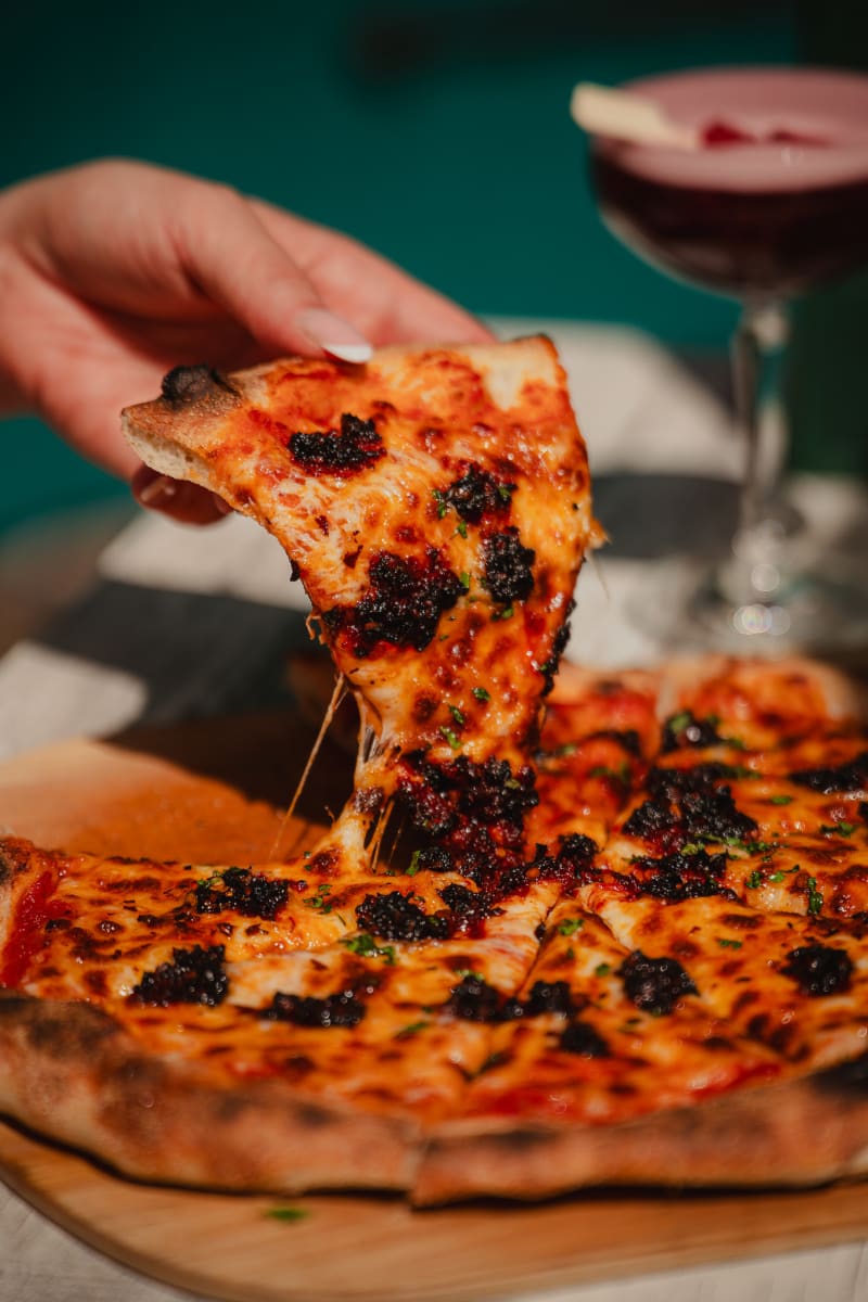 Cheese pull from a wood-fired olive pizza at Rose Street Garden, Edinburgh