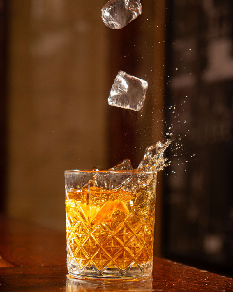 Old fashioned with ice splashing at Tiles Bar