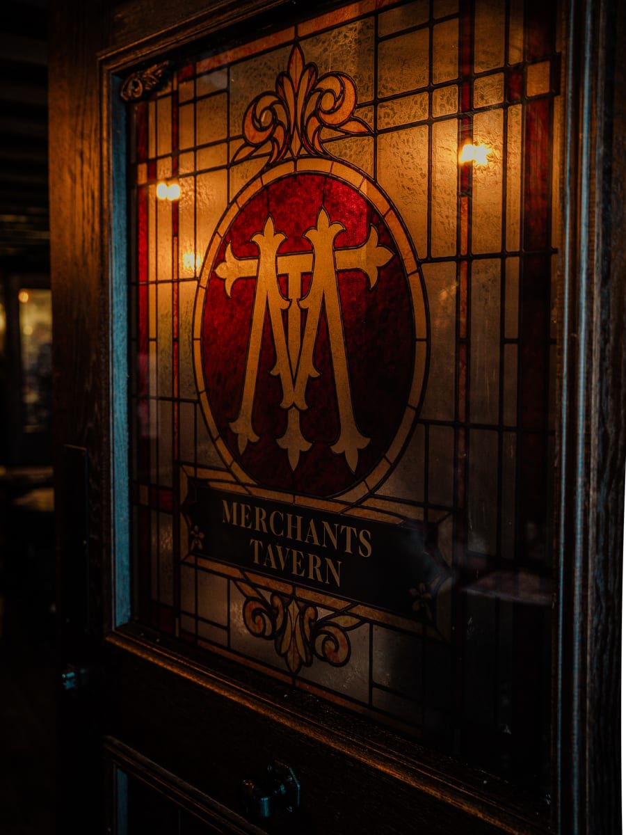 Stained glass window with the glowing tavern monogram at Merchant Tavern, Edinburgh