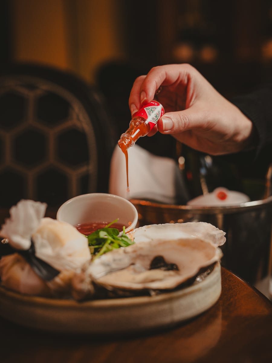 Hot sauce poured over fresh oysters on ice at The Dome