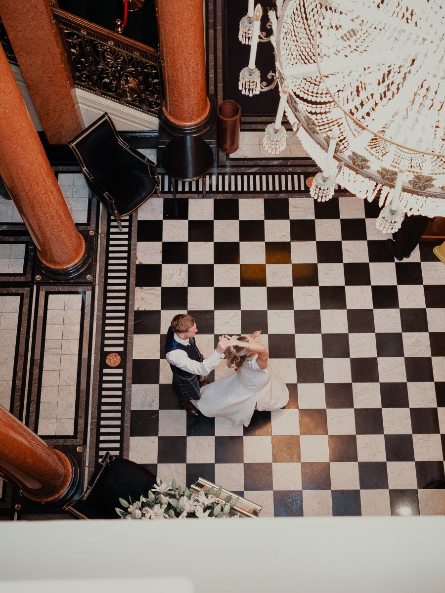 Wedding couple dancing on the checkerboard floor of The Dome seen from the gallery above