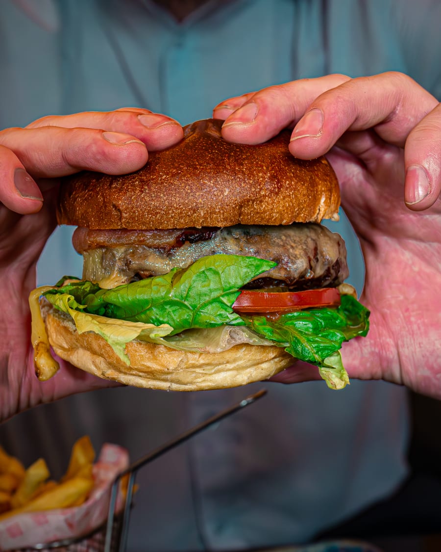 Hand holding a burger at The Pear Tree, Edinburgh