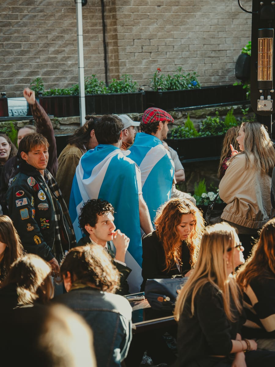 Fans wrapped in Scotland flags in the beer garden crowd at The Pear Tree, Edinburgh