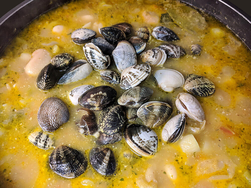 Guiso con alubias, laurel y almejas.