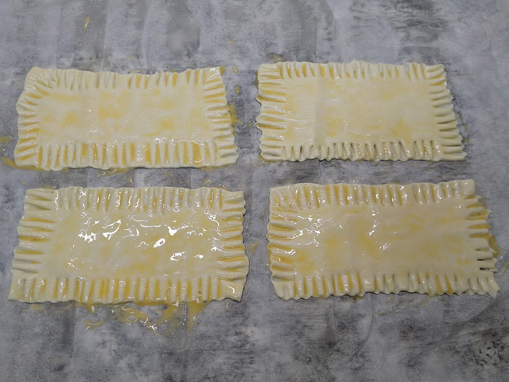 Masa de hojaldre fresca con bordes hechos y pintada con huevo batido.