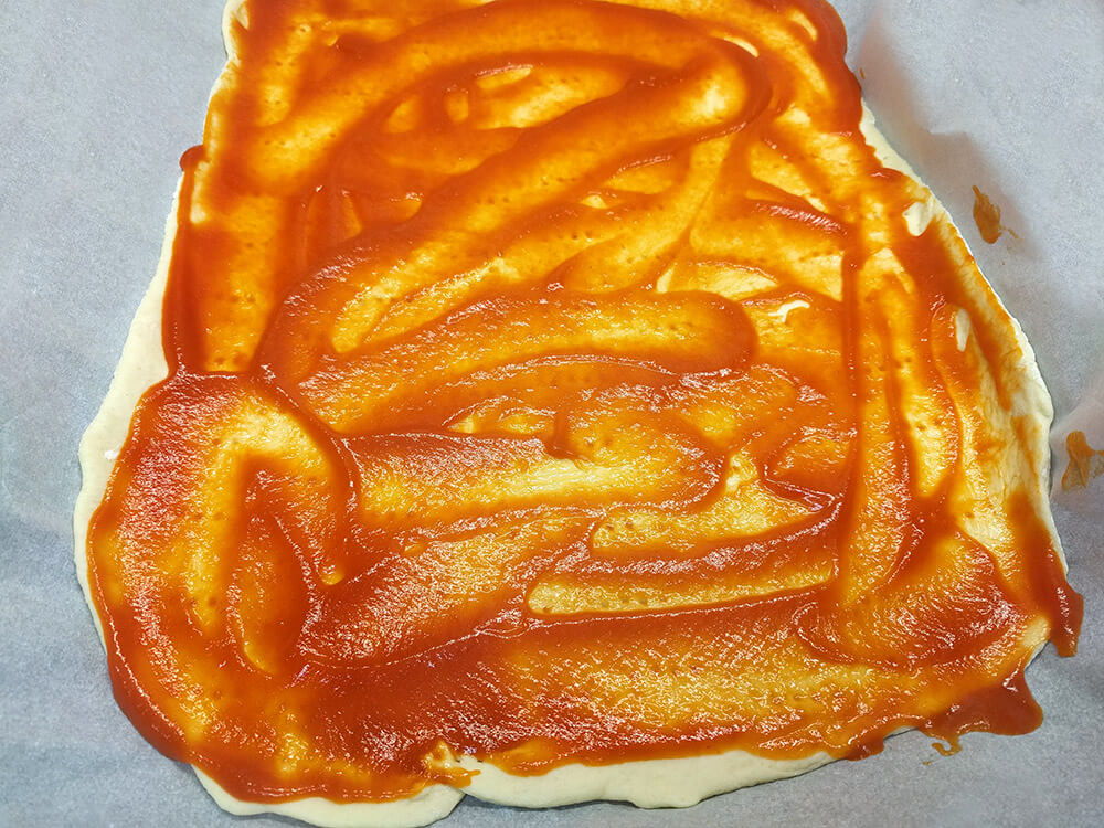Massa de pizza con tomate frito.