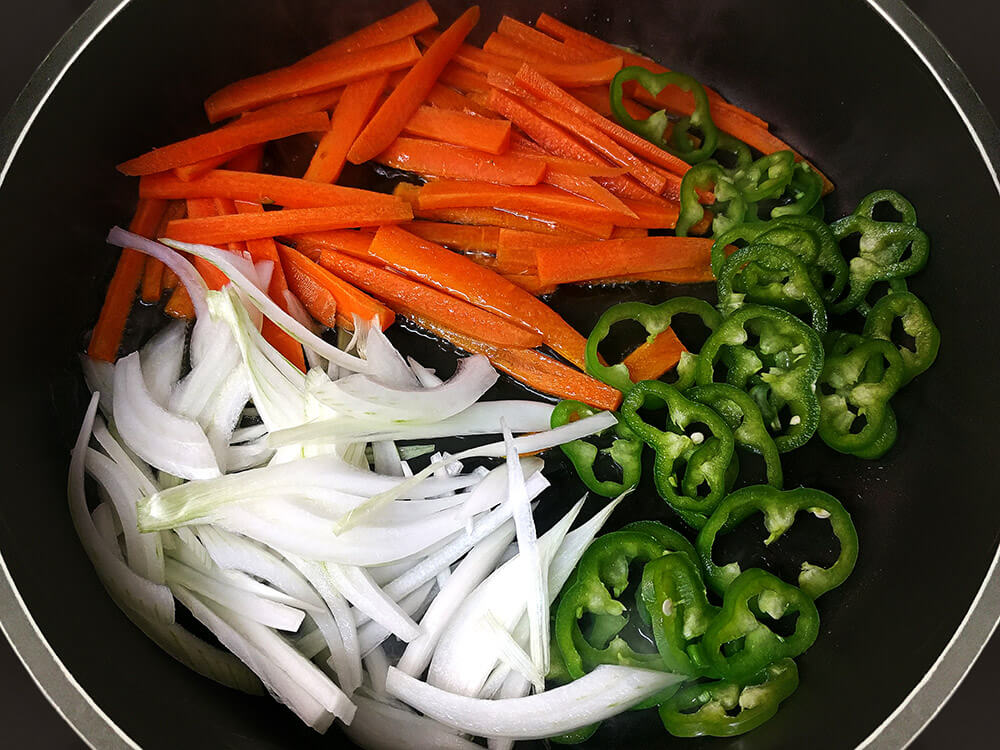 Cebolla, zanahoria y pimiento verde rehogando.