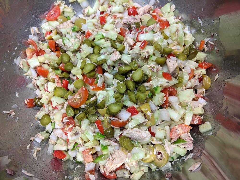 Pepino, pimiento verde, pimiento rojo, cebolla tierna, tomates cherry, pepinillos en vinagre y olivas cortados.