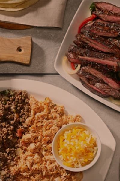 Table displayed with mexican food items, like fajitas, rice, beans and toppings