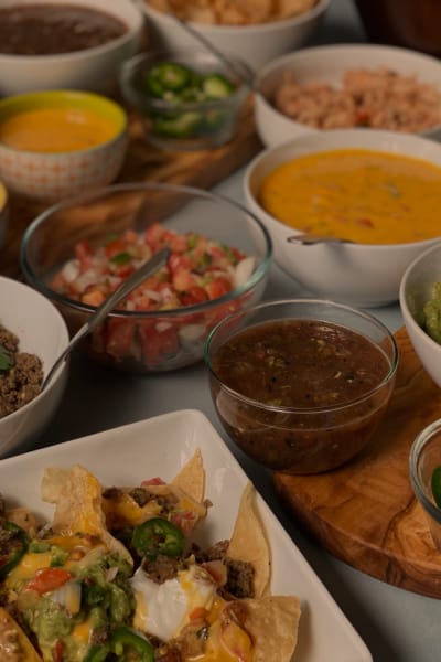 a layout of food that includes nachos, ground beef, guacamole, salsa and jaepenos