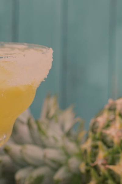 Uncle Julio's Pineapple Margarita in a margarita glass with a pineapple garnish next to a fresh pineapple.