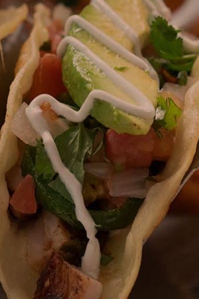 Three of Uncle Julio's Street Tacos on a platter with tomato, cilantro and avocado.