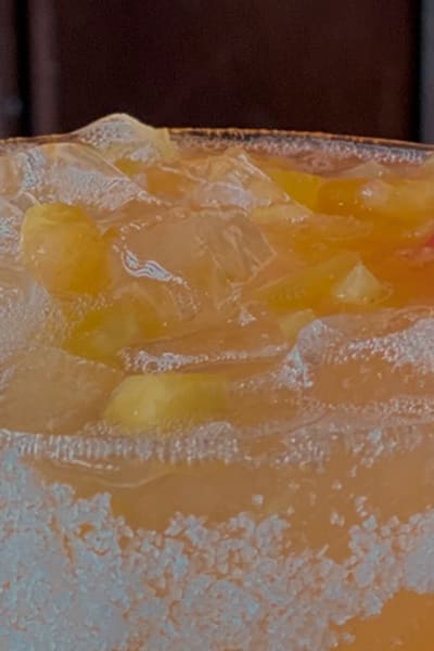 Uncle Julio's August margarita of the Month, peach, with a peach slice and sugar on the rim of the glass.