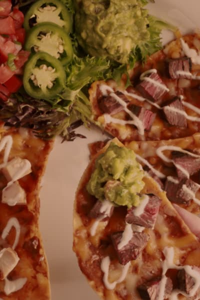 Chicken and steak fajita nachos with pico de gallo and guacamole on the side
