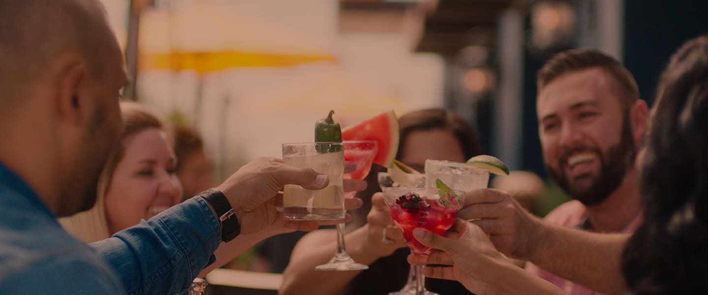 People's hands holding up beverages while dining together on the Uncle Julio's patio
