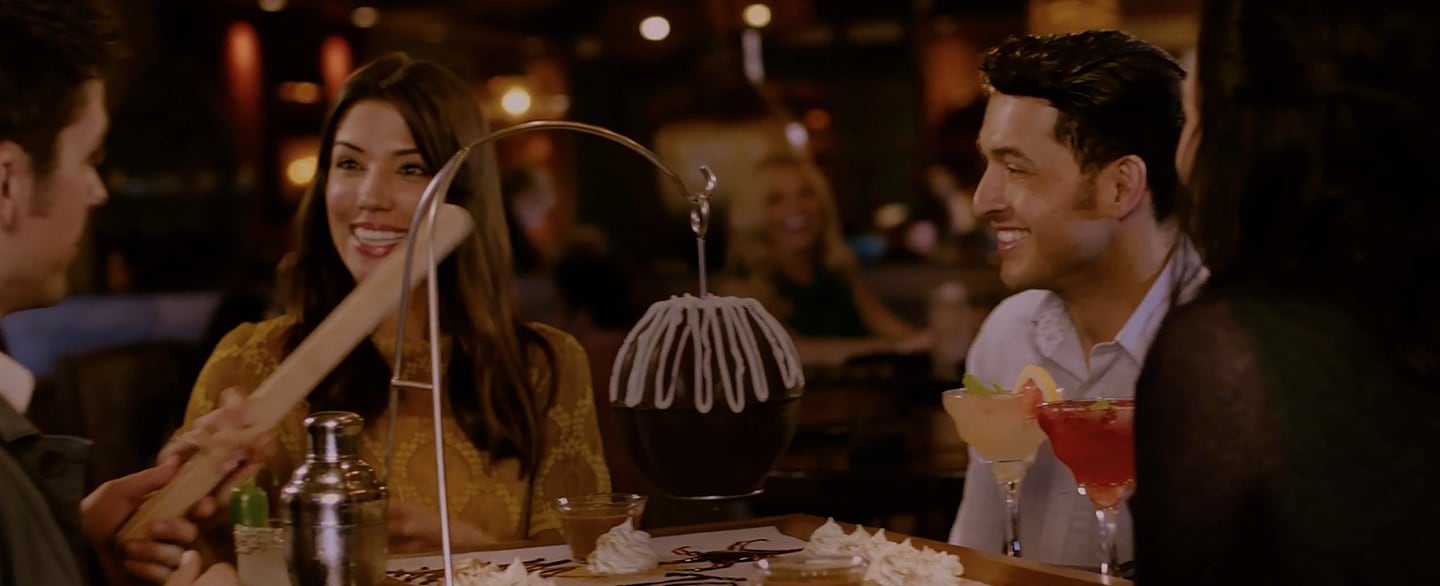 People sitting at a table with hanging pinata of chocolate