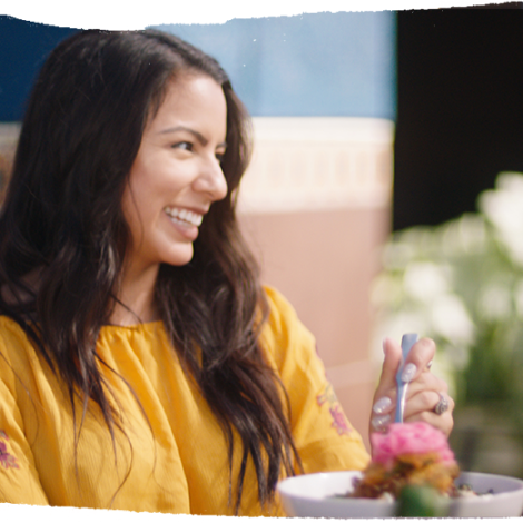 woman smiling sitting on the patio eating a lunch bowl