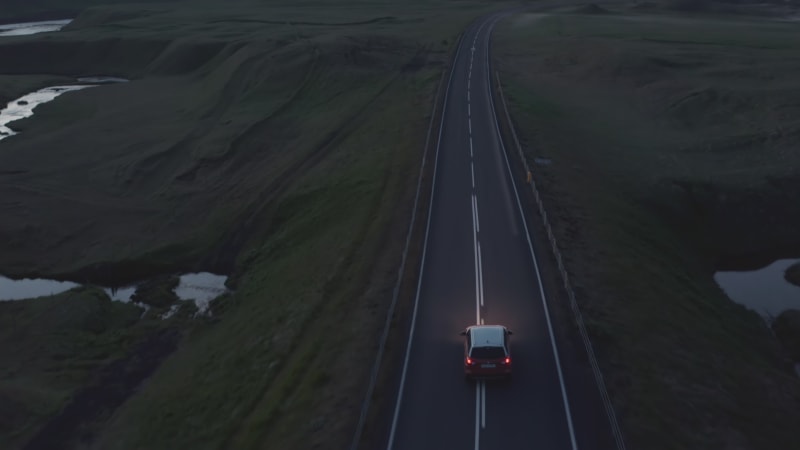 Birds eye view car peacefully driving on ring road, the most important highway in Iceland. Aerial view car driving along empty country road at evening. Commercial insurance drone view