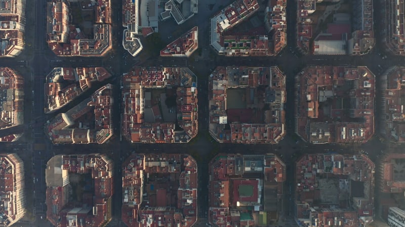 Town development arranged into square blocks. Birds eye shot of streets and buildings at golden hour. Barcelona, Spain