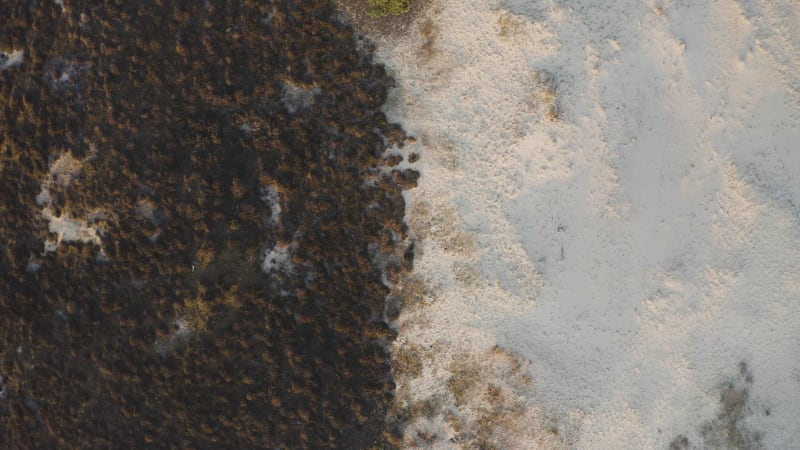 Rotating aerial view closing in on the sand dunes and small brown bushes