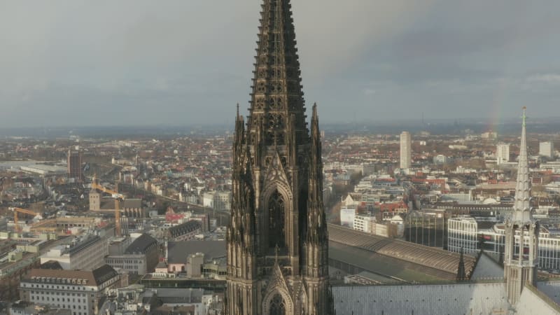 Close-up footage of beautiful gothic style tower with decorative turrets and ornaments. Cathedral Church of Saint Peter and town development in background. Cologne, Germany