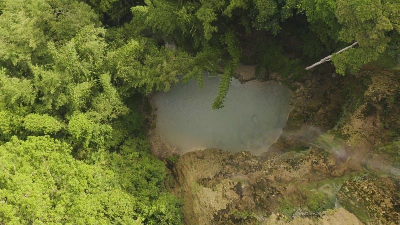 Upward shot of waterfall and rocky cliffs in lush rainforest