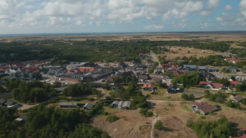 Slide and pan shot of centre of small town. Oksby and flat landscape from height. Summer vacation destination. Denmark