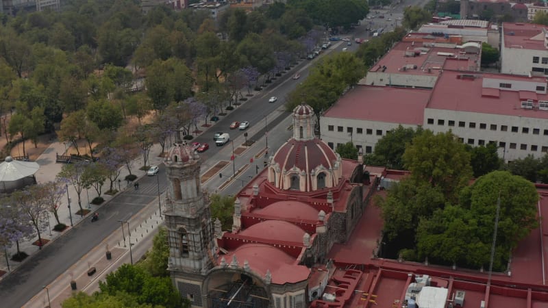 Elevated view of church with red dome and public town park Alameda Central. Drone camera flying over building in downtown. Mexico city, Mexico.