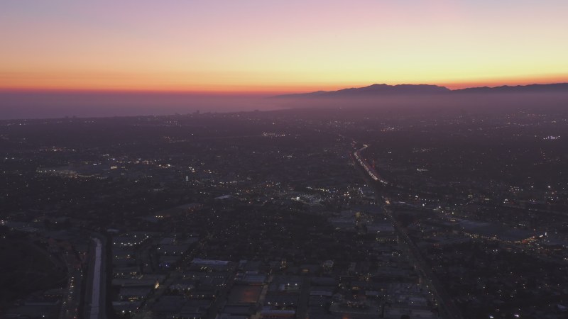 Wide view of Los Angeles and Santa Monica, California towards pacific ocean from Culver City at Dusk, Night with Purple Sky and glowing city lights with Mountain Silhouette