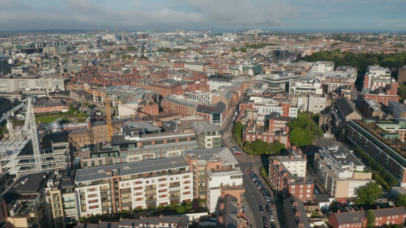 Aerial panoramic footage of city centre in bright afternoon sun. Various town buildings in flat landscape. Dublin, Ireland