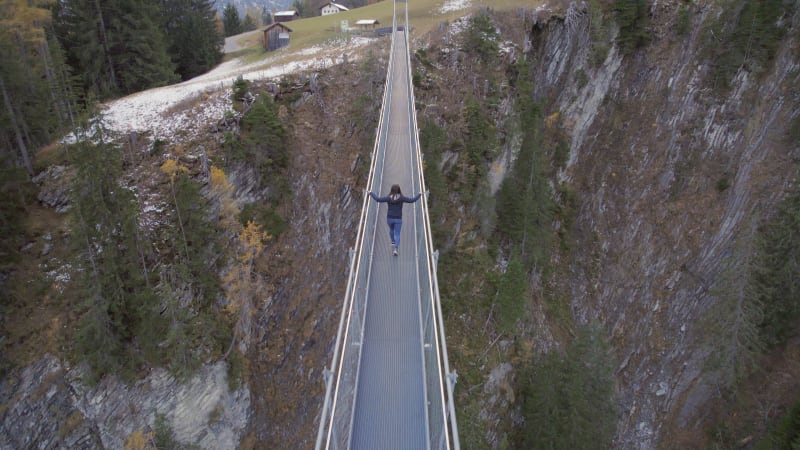 Girl Crossing a Footbridge Spanning a Ravine