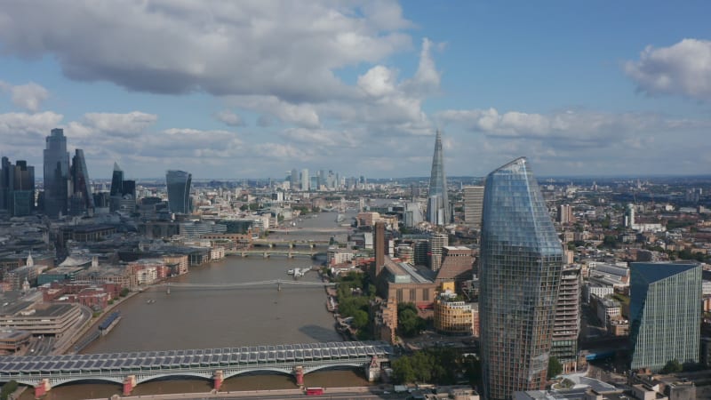 Fly around One Blackfriars tall building on bank of River Thames. Aerial panoramic view of city during sunny day. London, UK