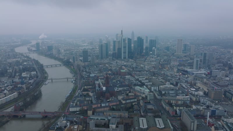 Fly above metropolis. Group of downtown skyscrapers towering above town development. Bridge spanning wide river. Frankfurt am Main, Germany