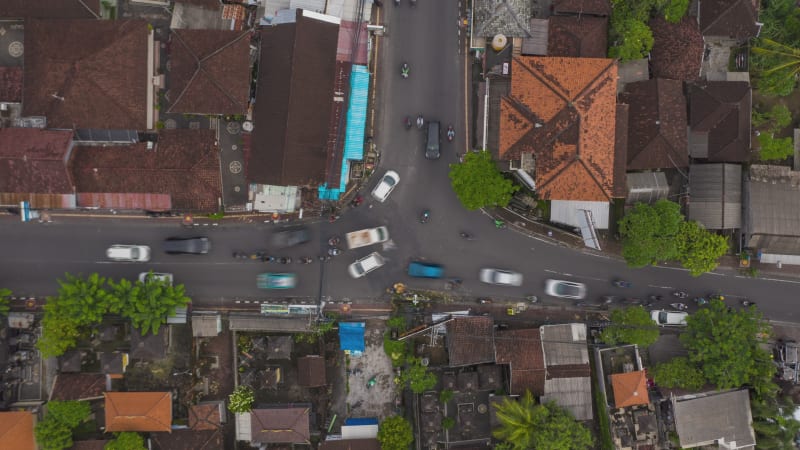 Top down overhead aerial view timelapse of busy rush hour traffic at the intersection in Canggu, Bali. Typical busy car and motorcycle traffic at urban crossroads on the streets of Bali, Time Lapse