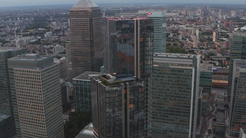 Ascending footage of top part of South Quay Plaza building. Glossy glass covered skyscraper on Isle of Dogs. Group of tall towers in Canary Wharf business hub. London, UK