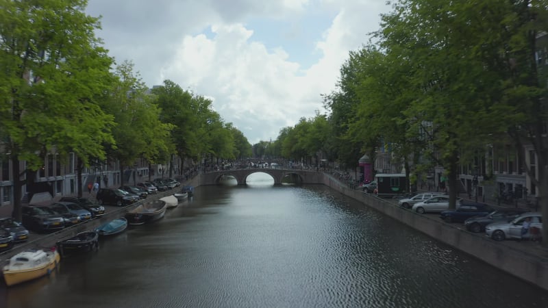 Establisher over Amsterdam Canal with Boat and Dutch Flag waving in wind, backwards Aerial