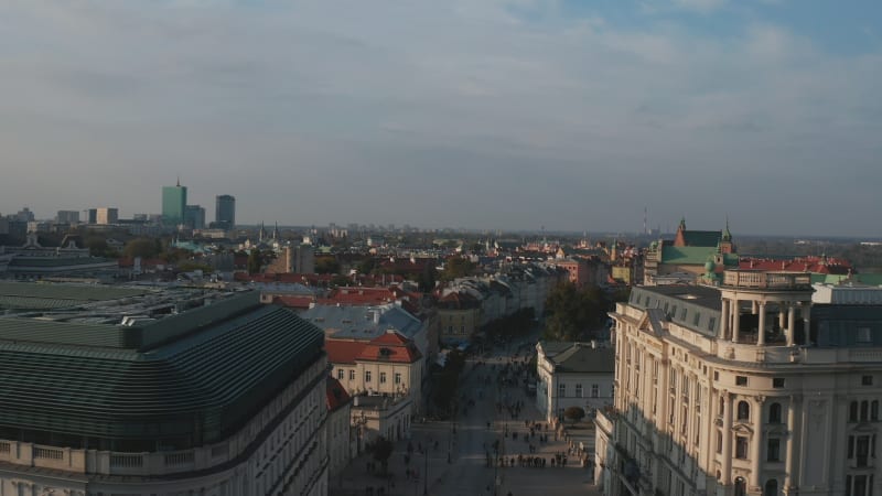 Elevated view of historic part of city in golden hour. People walking on Krakowskie, street with sights. Warsaw, Poland