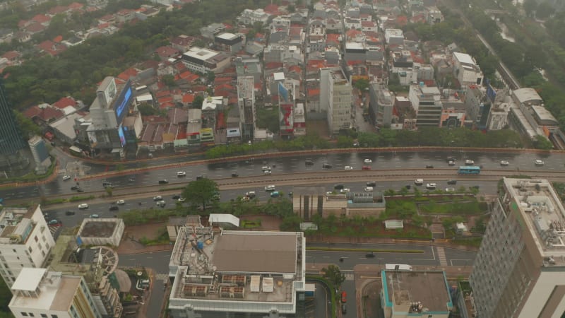 Aerial dolly tilting shot closing in on multi lane highway in urban city center on a rainy day