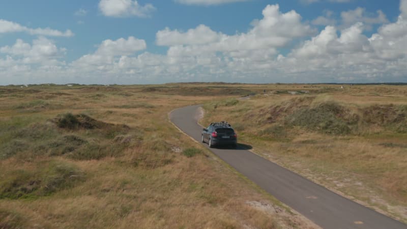 Tracking of car driving on narrow path in flat countryside. Approaching to oncoming cyclists. Denmark