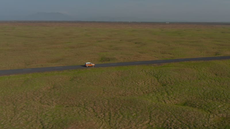 Drone view sliding car travelling peacefully on Ring Road in Iceland. Aerial view tourist driving car discovering wilderness in Iceland with idyllic panorama landscape