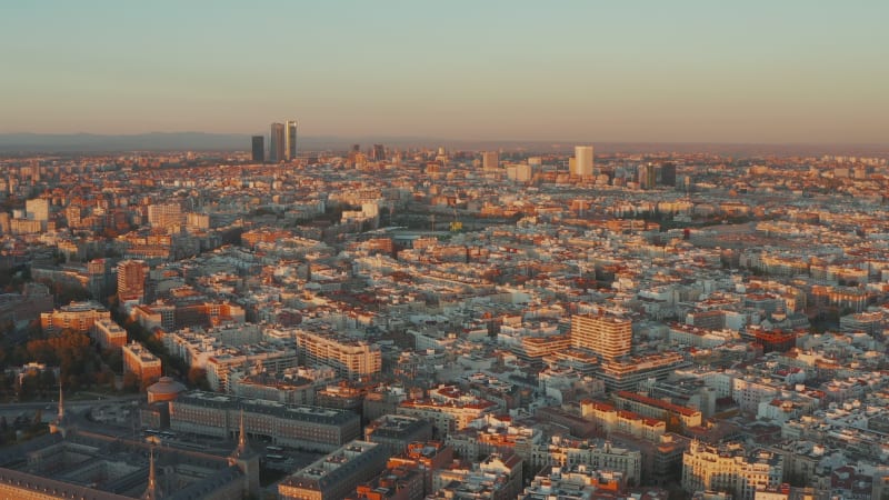 Aerial panoramic footage of cityscape at sunset. Budlings lit by bright orange light.