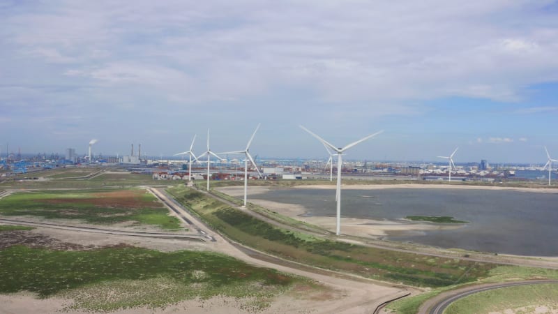 Spinning wind turbines by a busy industrial port in the Netherlands