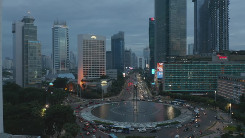 Slow aerial dolly shot of busy traffic on a roundabout in modern city center in Jakarta, Indonesia