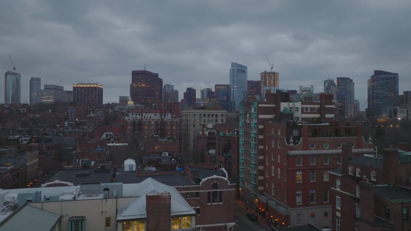 Residential brick buildings in Back Bay borough and downtown high rise office towers against overcast sky at twilight. Boston, USA