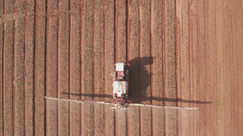 Pesticide Sprayer Tractor working on a large field, Aerial follow footage.