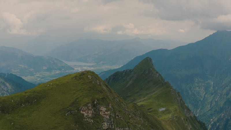 Flying past green mountain peaks, revealing the valley below