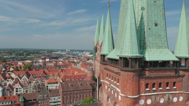 Slide and pan reveal of medieval city centre behind St. Peters church tower. Brick gothic buildings. Luebeck, Schleswig-Holstein, Germany