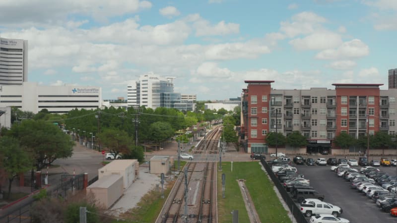 Aerial view of empty double-track railway line leading through town. Cars driving on rail crossing. Forward flying drone. Dallas, Texas, US