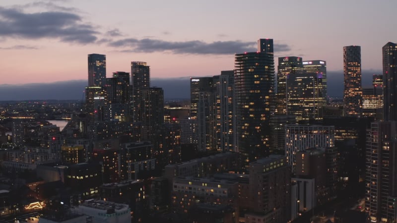 Evening slide and pan footage of tall downtown office buildings in blue hour. Parallax effect. London, UK