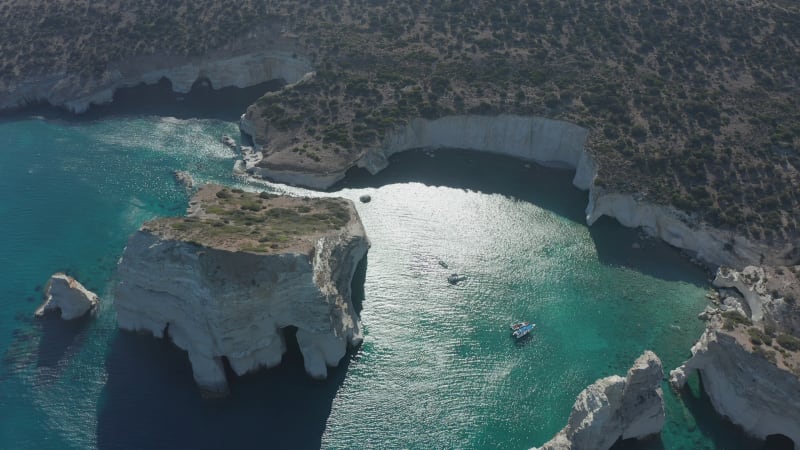 Aerial Wide Establishing Shot of Tropical Bay in Greece with White Rocks and Boats in the Ocean